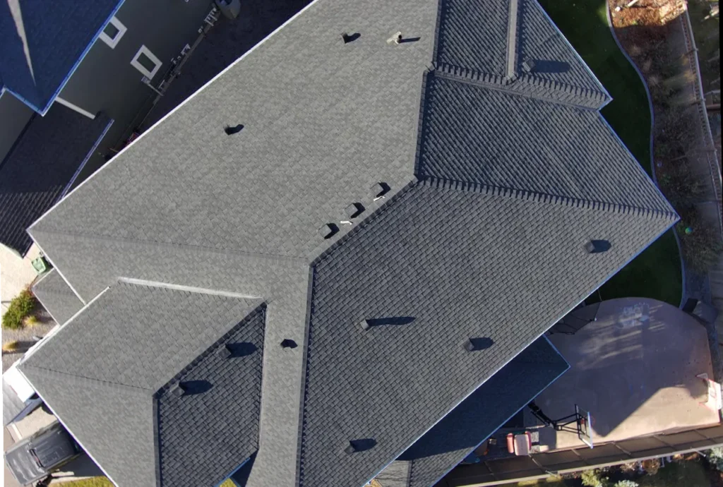 Hips and ridge caps on a new shingle roof in Aspen Woods, Calgary, drone view