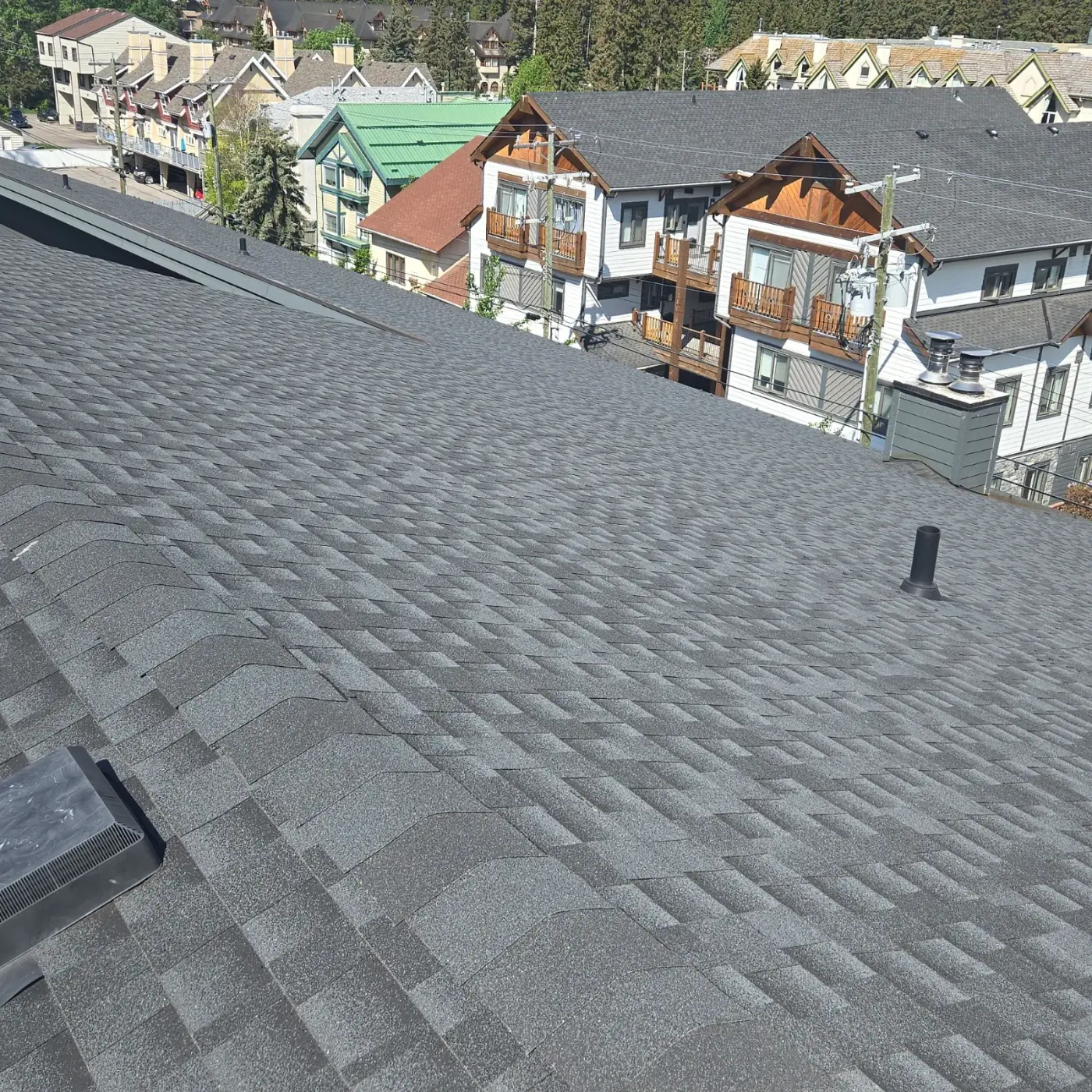 Shingle roof on a large Banff condo building during our roof inspection, with neighbouring Banff buildings behind