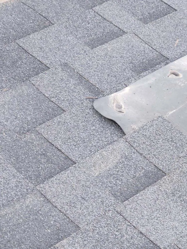 Lifted, broken shingle tab found during a roof inspection in Bankview, Calgary