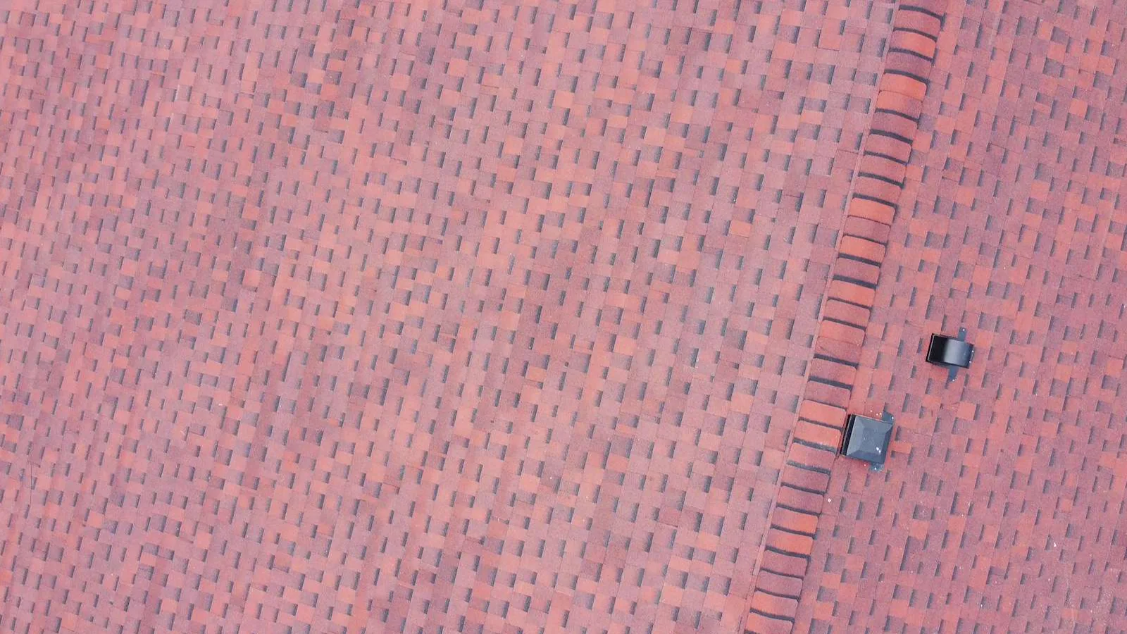 Close-up of new red architectural shingles and hip ridge cap on a Dalhousie, Calgary roof