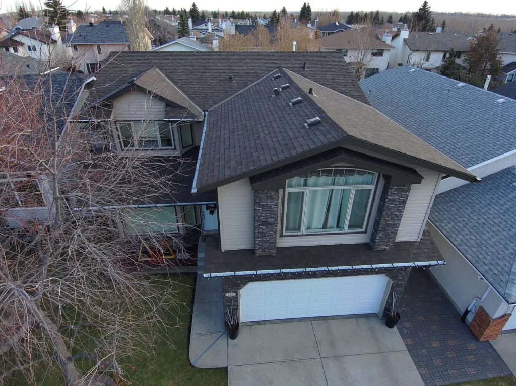 New dark architectural shingle roof on a two-storey home on Riverside Mews in Riverbend, Calgary, drone view