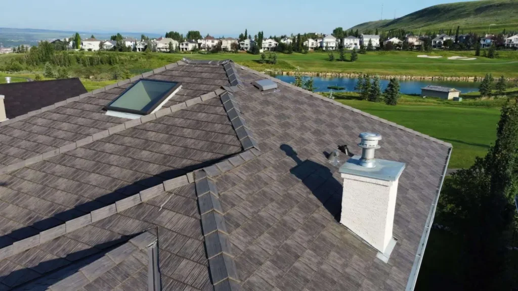 Close view of a finished rubber shake roof with chimney and skylight in Cochrane, AB