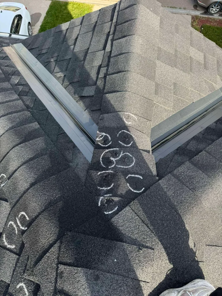 Hail hits chalk-marked beside a valley during a roof inspection in Saddle Ridge, Calgary