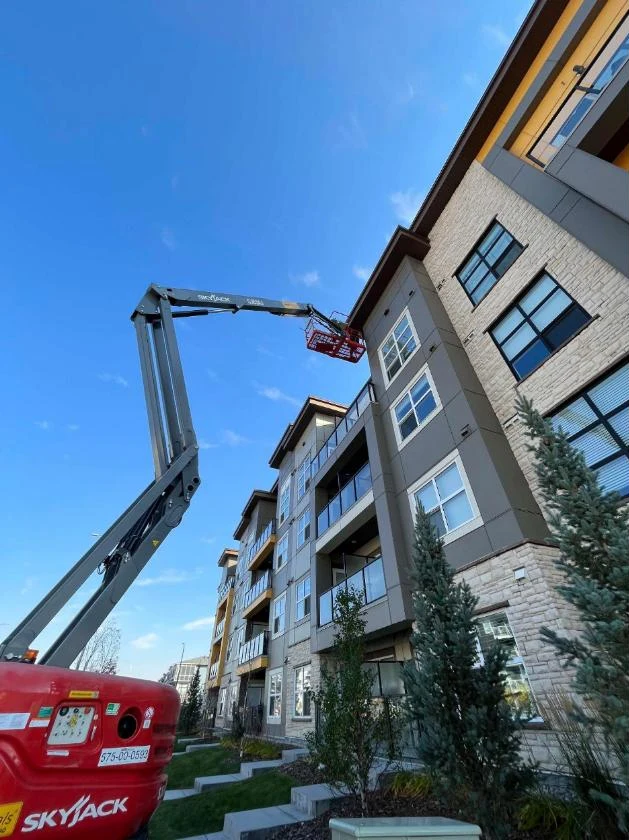 Manlift reaching the top floor of a long condo building, Calgary, AB