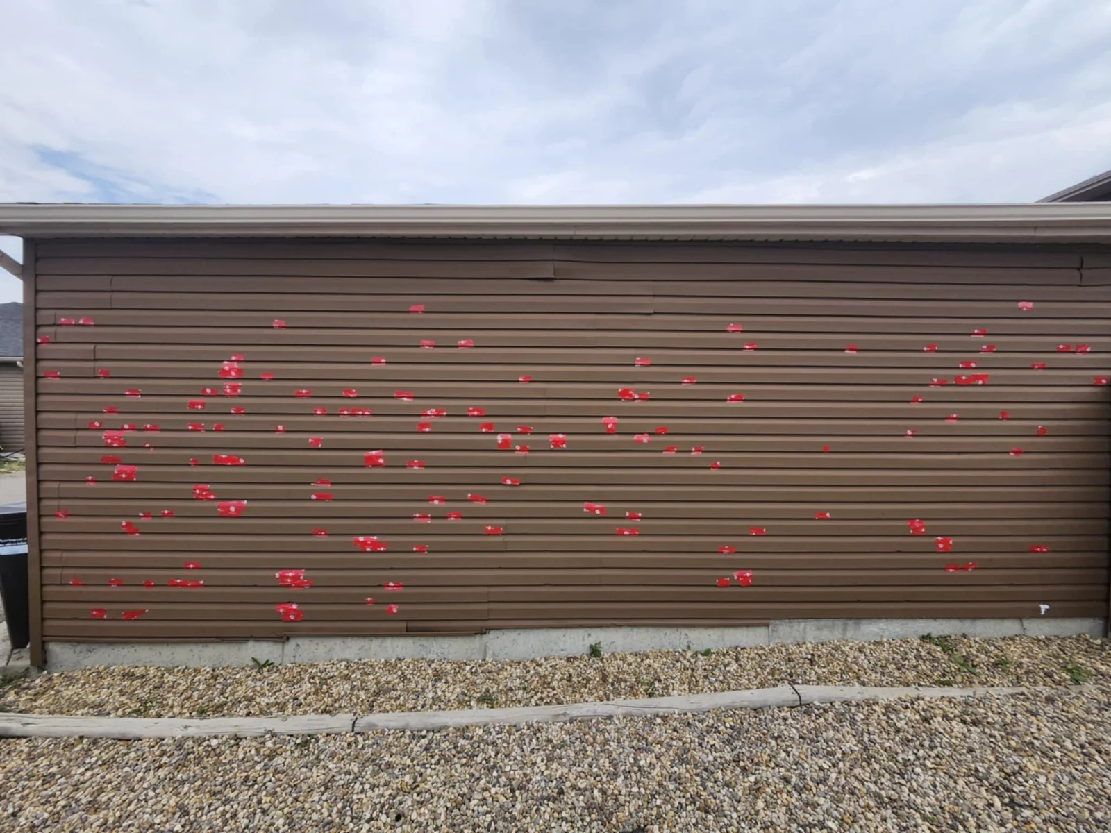 Hail-damaged siding with every impact marked in red, Calgary, AB