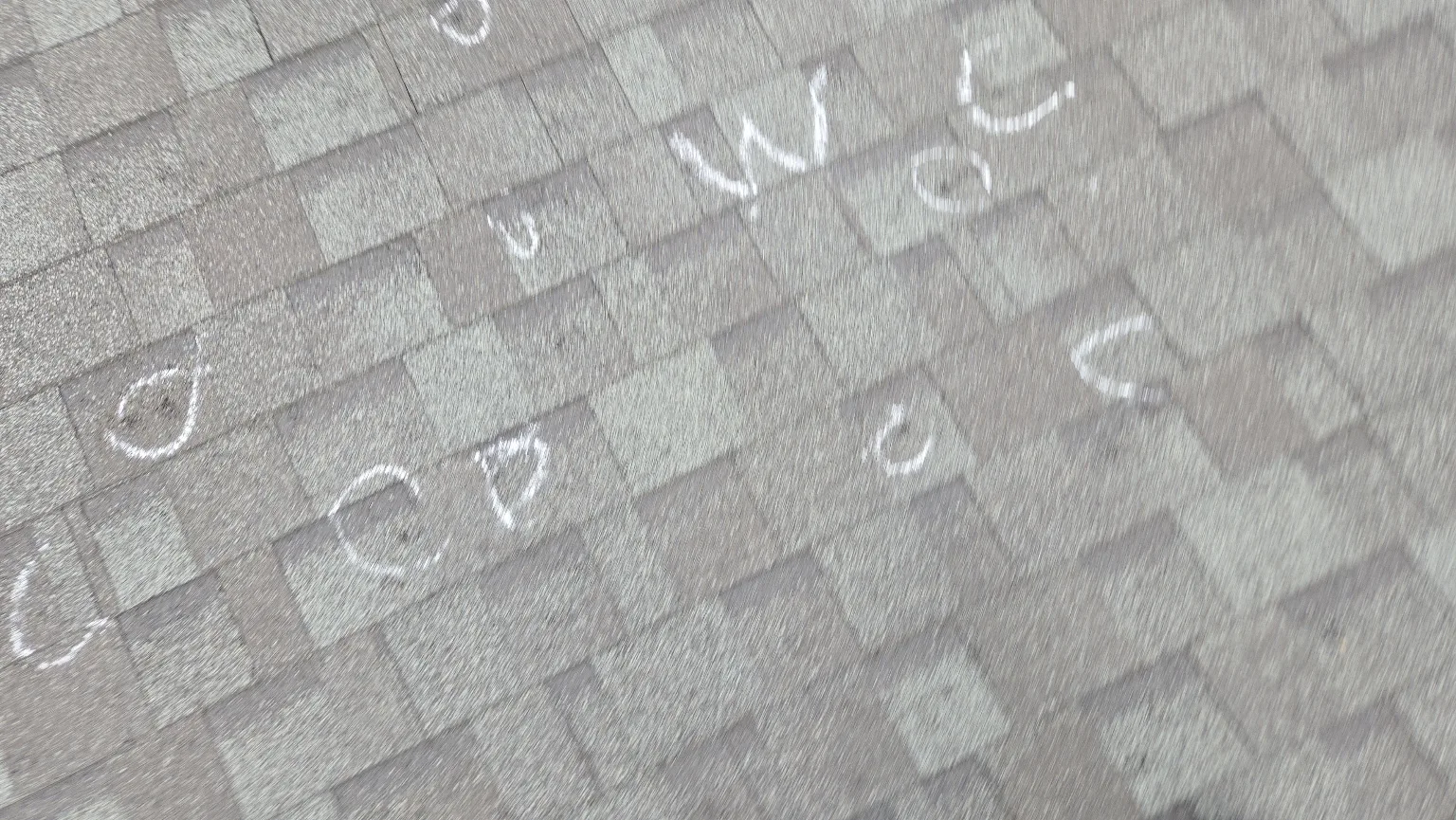 Hail hits marked in chalk on asphalt shingles during an inspection in Calgary