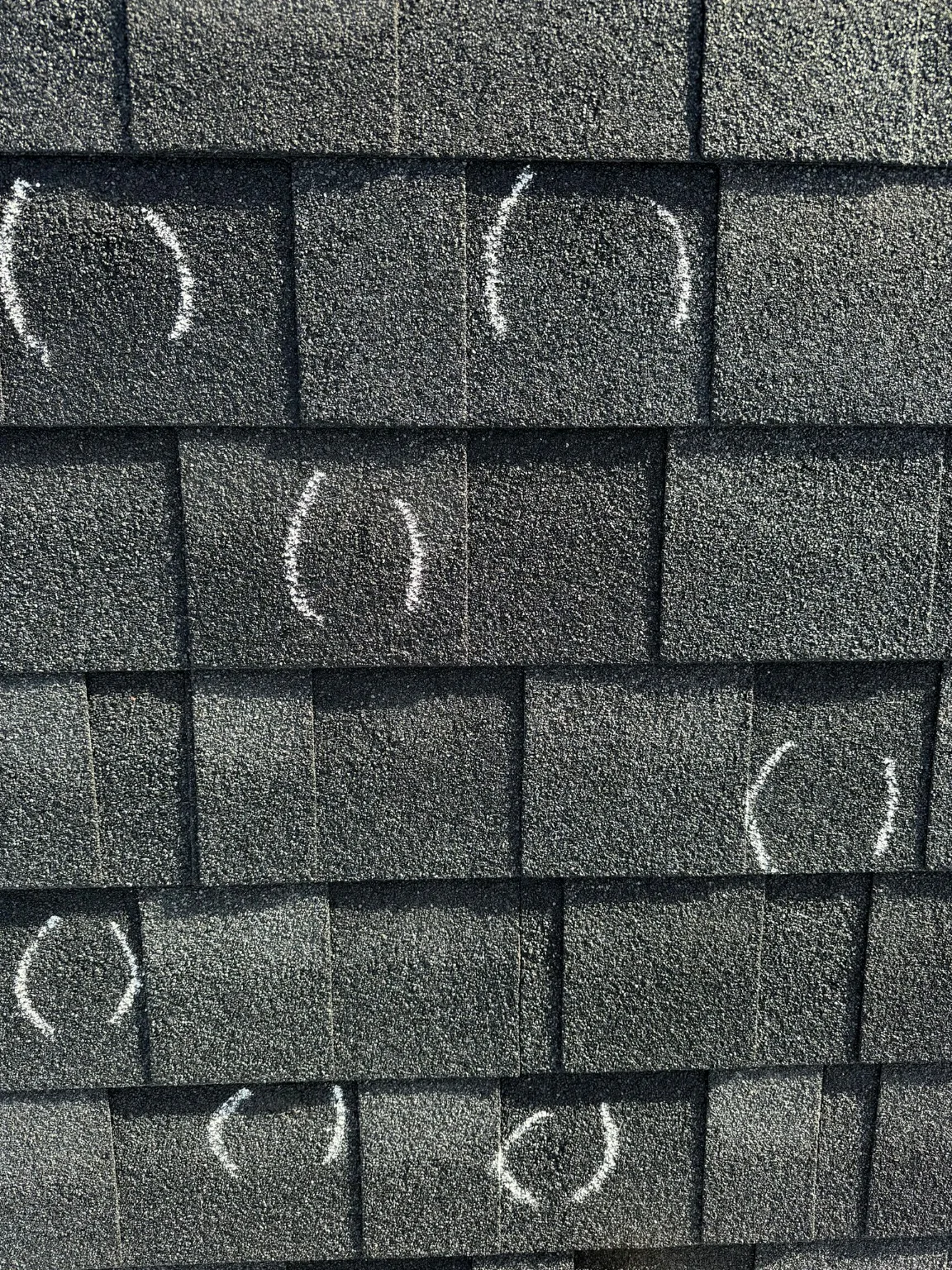 Hail hits circled on asphalt shingles during a re-inspection in Calgary