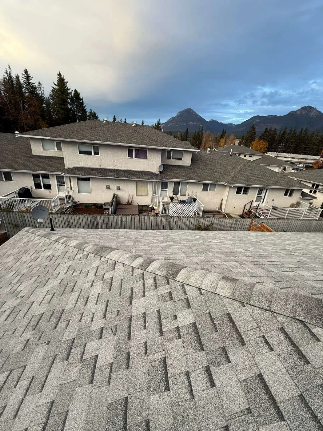 New grey architectural shingle roofs across the strata complex, with the mountains behind, Golden, BC