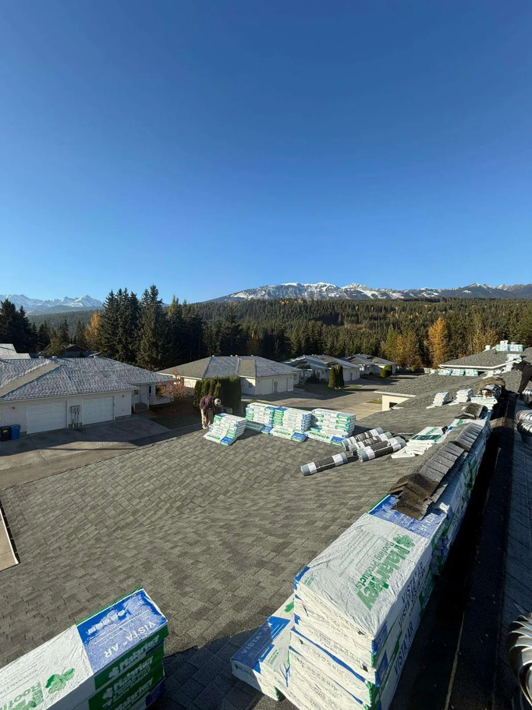 The original strata roofs before replacement, with the new shingles loaded on the roofs and ready, Golden, BC