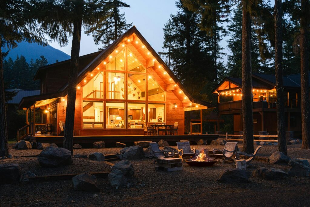 Mountain cabin with a tall wall of gable windows lit up at dusk