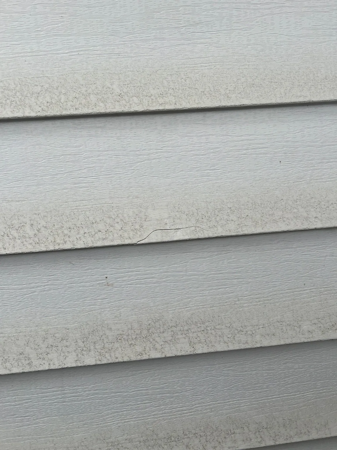 Dents in vinyl siding found during an exterior assessment, Calgary